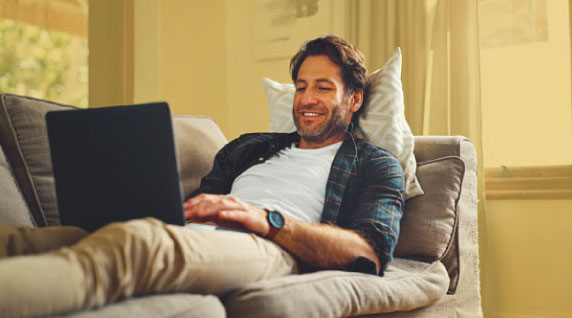 Male laying on the couch using his laptop.