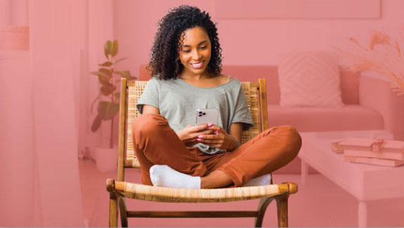 Woman sitting in a chair looking at her phone.